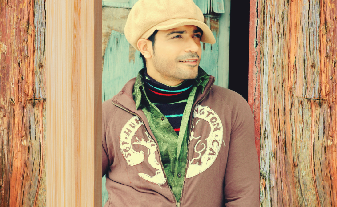 Nitin Sahrawat wearing a brown jacket, green scarf, and beige cap standing against a wooden wall, showcasing his 15-year acting career, a chapter he discusses in his founder's story blog on reinvention.